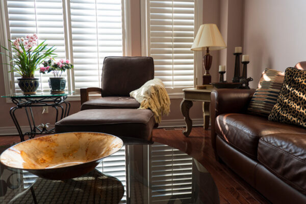 A stylish modern living room with brown leather furniture, glass tables and interesting accents.